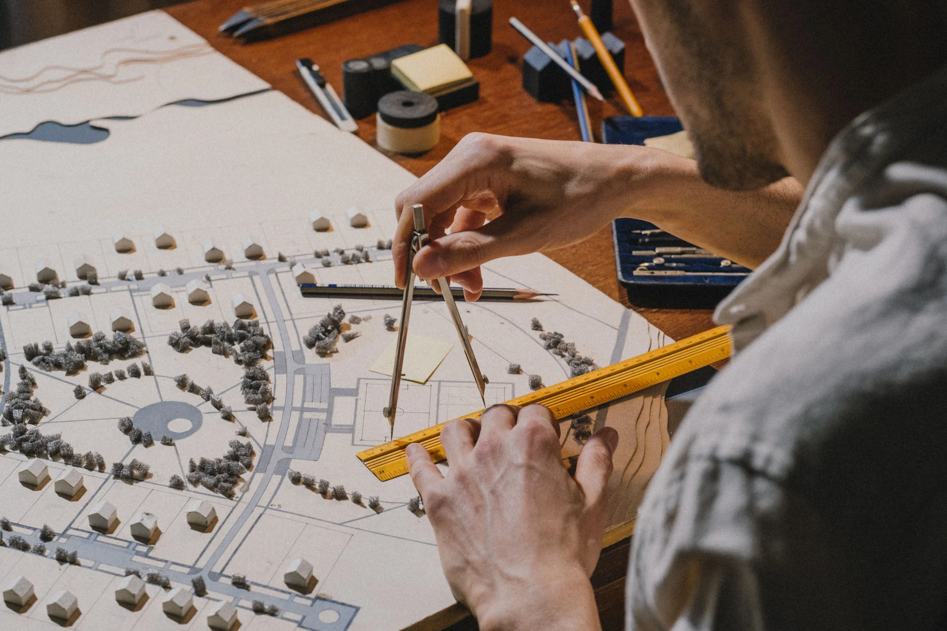 An architect measuring a site plan model of new homes with a compass and ruler